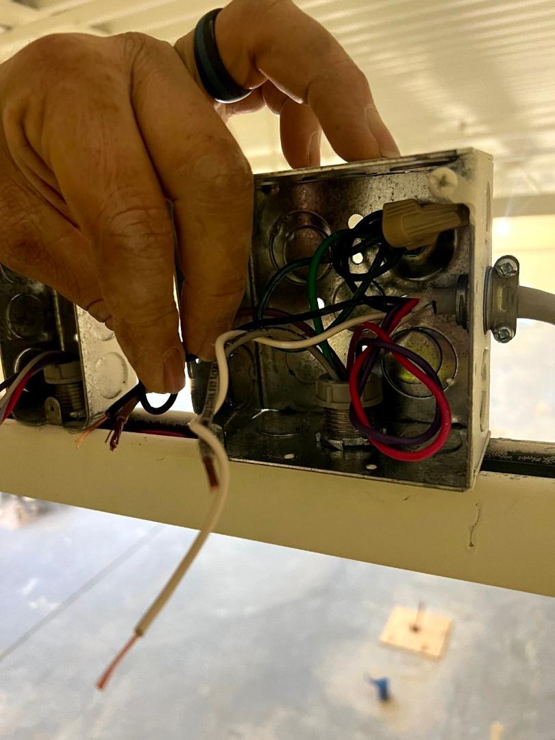 Technician inspecting electrical junction box wiring during compliance testing